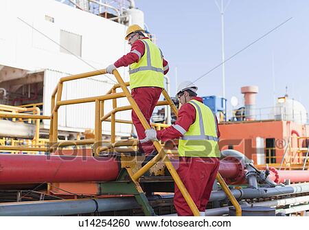 Workers climbing over pipes on oil rig View Large Photo Image Stock Image - Workers climbing over pipes on oil rig. Fotosearch