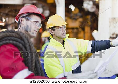 Workers examining blueprints on oil rig View Large Photo Image Stock Photograph - Workers examining blueprints on oil rig. Fotosearch