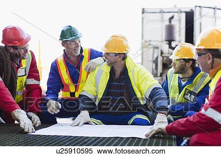 Workers examining blueprints on oil rig View Large Photo Image Stock Photography - Workers examining blueprints on oil rig. Fotosearch