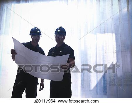 Picture - Workers examining blueprints together. Fotosearch