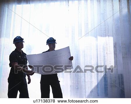Stock Photo - Workers examining blueprints together. Fotosearch