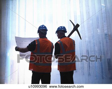 Stock Photograph - Workers examining blueprints together. Fotosearch
