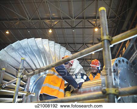 Stock Image - Workers inspect turbine in power station. Fotosearch