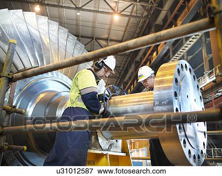 Stock Photo - Workers inspect turbine in power station. Fotosearch
