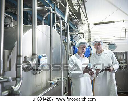 Stock Photo - Workers inspecting goat yogurt in dairy. Fotosearch