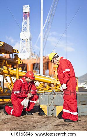 Workers on oil rig examining equipment View Large Photo Image Stock Photography - Workers on oil rig examining equipment. Fotosearch