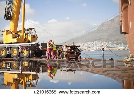 Workers on oil rig standing by crane View Large Photo Image Stock Photography - Workers on oil rig standing by crane. Fotosearch