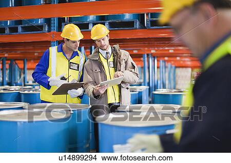 Workers reading clipboards in warehouse View Large Photo Image Picture - Workers reading clipboards in warehouse. Fotosearch