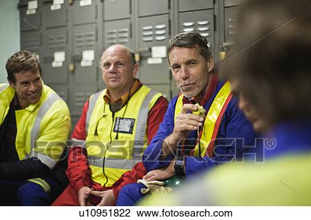 Stock Image - Workers sitting in locker room. Fotosearch