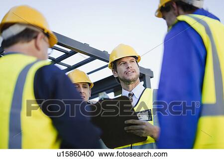 Workers talking at construction site View Large Photo Image Stock Image - Workers talking at construction site. Fotosearch