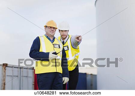 Stock Image - Workers talking in shipping yard. Fotosearch
