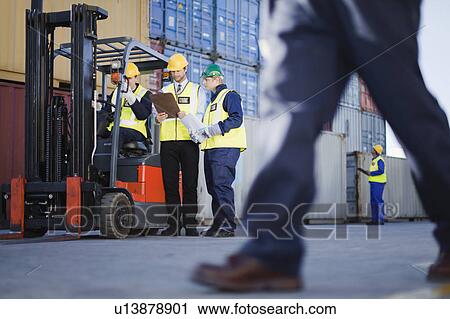 Stock Image - Workers talking in shipping yard. Fotosearch