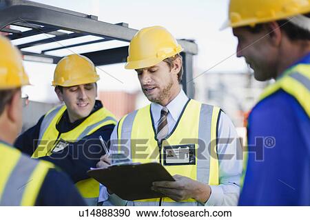 Stock Image - Workers talking in shipping yard. Fotosearch