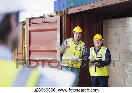 Stock Photograph - Workers talking in shipping yard. Fotosearch