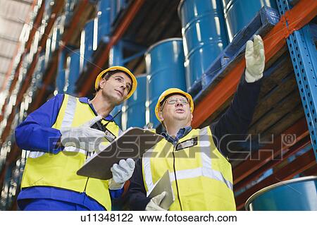 Stock Image - Workers talking in warehouse. Fotosearch