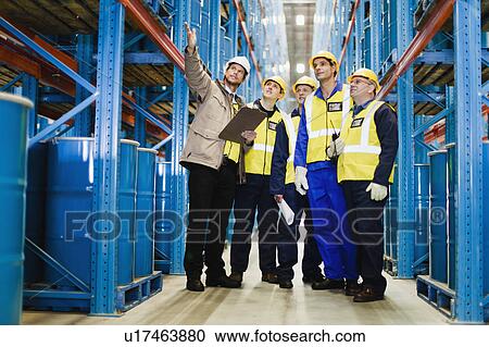 Stock Image - Workers talking in warehouse. Fotosearch