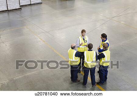 Stock Image - Workers talking in warehouse. Fotosearch