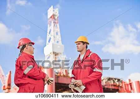 Stock Image - Workers talking on oil rig. Fotosearch