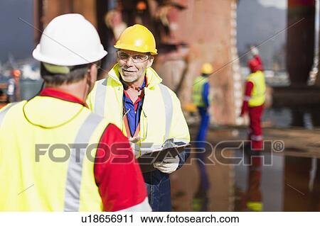 Stock Image - Workers talking on oil rig. Fotosearch