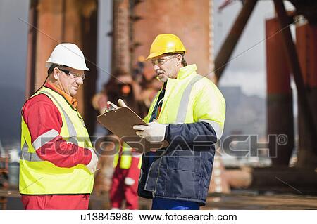 Stock Photograph - Workers talking on oil rig. Fotosearch