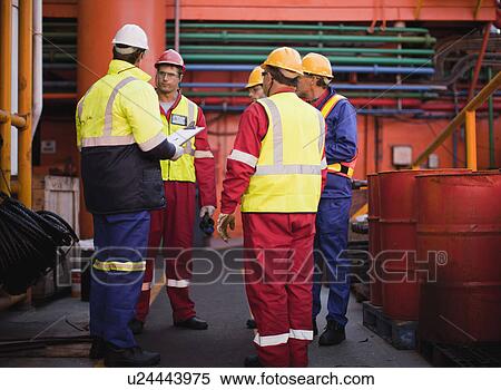 Stock Photography - Workers talking on oil rig. Fotosearch