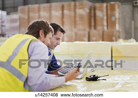 Workers using laptop in warehouse View Large Photo Image Stock Photo - Workers using laptop in warehouse. Fotosearch
