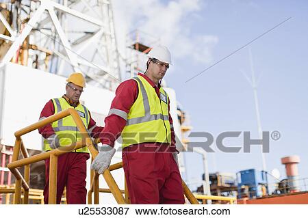 Stock Photo - Workers walking on oil rig. Fotosearch