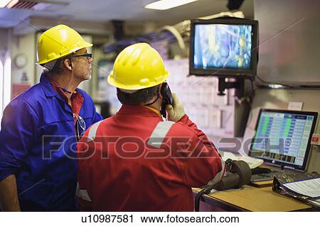 Stock Image - Workers watching security cameras. Fotosearch