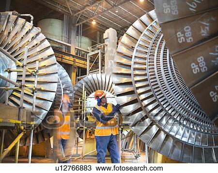 Stock Image - Workers with turbines in power station. Fotosearch