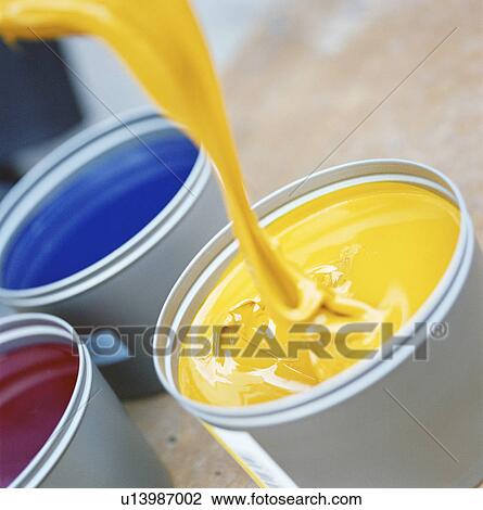 Stock Image - Yellow paint pouring into bucket. Fotosearch