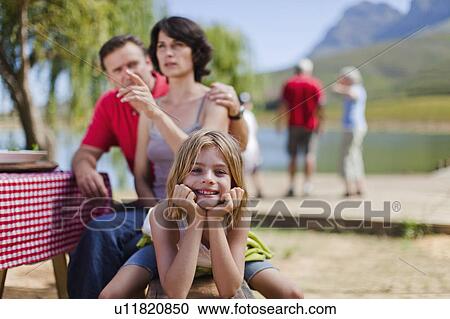 Stock Image - Young girl smiling at picnic bench. Fotosearch