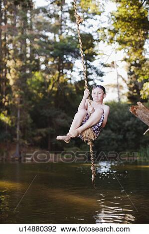 Young girl using rope swing over lake View Large Photo Image Stock Image - Young girl using rope swing over lake. Fotosearch