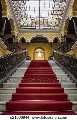 Picture - Archbishops' palace: Interior detail of red-carpeted staircase, mahogany balustrades, stained glass ceiling with yellow stucco walls: Spanish Colonial style, Lima, Peru. Fotosearch