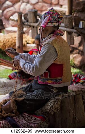 Stock Photo - Close up of man in traditional Peruvian clothing hand-spinning wool with spindle, Awanacancha llama farm, Sacred Valley, Cuzco, Peru. Fotosearch