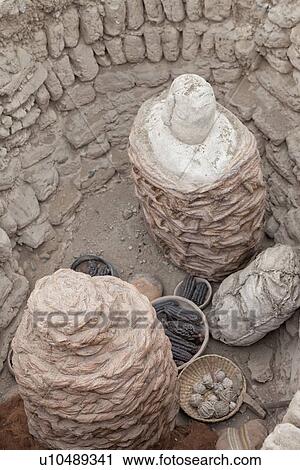 Stock Image - Huaca Pucllana: detail from above of adobe mud brick burial site with woven baskets, black corn cobs and other remains, dating back to Lima culture of 400AD, Lima, Peru. Fotosearch
