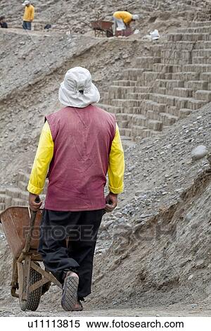 Stock Photography - Huaca Pucllana: view of workman with wheelbarrow, restoration of adobe mud brick walls dating back to Lima culture of 400AD, Lima, Peru. Fotosearch