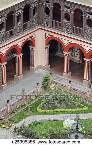 Stock Photograph - Iglesia de Santo Domingo cloister with red and white arches, ornate wooden balustrade above, Spanish tile decor, Spanish Baroque, aerial detail view, Lima, Peru. Fotosearch