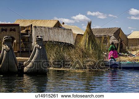 Stock Image - Lake Titicaca: islands of Uros with family on reed island, reed huts and prows of reed boats visible, Peru. Fotosearch