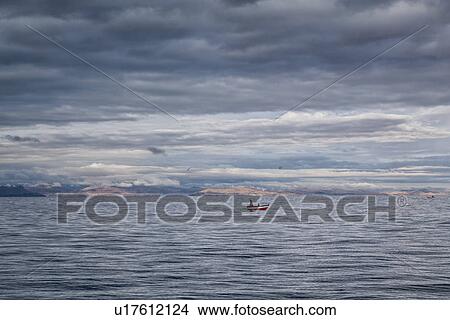 Lake Titicaca: Llachon peninsula, fishing boatout in lake at sunrise with stormy sky, Peru View Large Photo Image Picture - Lake Titicaca: Llachon peninsula, fishing boatout in lake at sunrise with stormy sky, Peru. Fotosearch