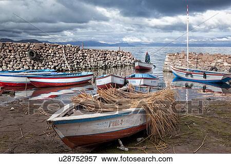 Lake Titicaca: Llachon peninsula, fishing boats moored at sunrise in harbour inlet, with fisherman returning in rowing boat, Peru View Large Photo Image Stock Photo - Lake Titicaca: Llachon peninsula, fishing boats moored at sunrise in harbour inlet, with fisherman returning in rowing boat, Peru. Fotosearch