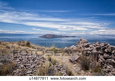 Stock Image - Lake Titicaca: Llachon peninsula, view of lake and island from summit, sunny early morning light, Peru. Fotosearch