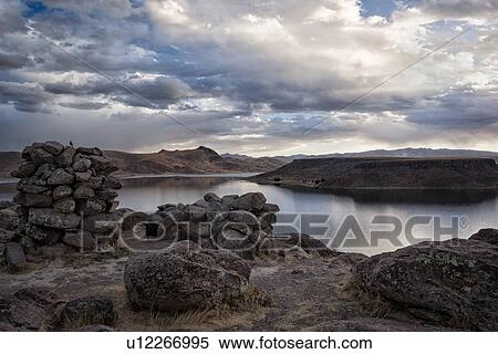 Stock Photography - Lake Titicaca: Sillustani funerary towers with view across Lake Umaya at sunset, dramatic storm clouds and light, Peru. Fotosearch