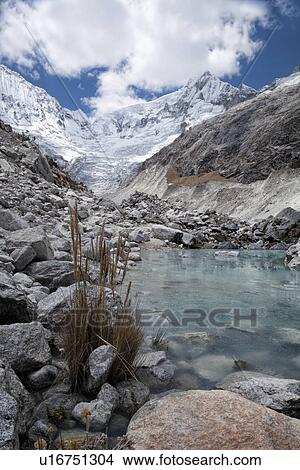 Picture - Llaca valley: glacier and moraine, with river and snow-capped mountains beyond, blue sky and dramatic clouds, Cordilleras, Peru. Fotosearch