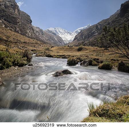Stock Photo - Llaca valley: mountain stream with motion blur, and snow-capped mountains beyond, blue sky, Cordilleras, Peru. Fotosearch