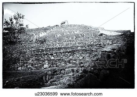 Stock Photo - Machu Picchu Inca ruins: monochrome view of Caretaker's Hut seen from below agricultural terraces, creating stark graphic pattern of stonework, Machu Picchu, Sacred Valley, Peru. Fotosearch