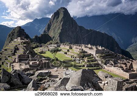 Stock Photo - Machu Picchu Inca ruins: view of Eastern Urban sector and Western Royal Palaces and Intihuatana, with Huayna Picchu mountain in evening sunlight after storm, Machu Picchu, Sacred Valley, Peru. Fotosearch