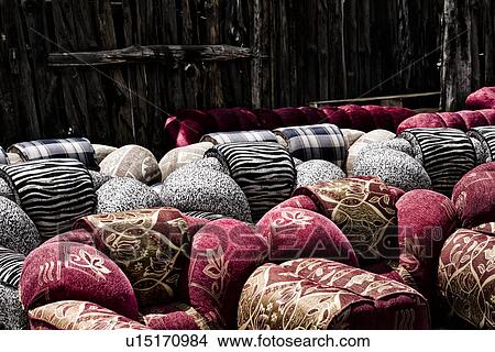 Picture - Outdoor furniture shop in Nakuru town: detail of brightly coloured red, and black and white sofas against wooden fence backdop, Nakuru, Kenya,. Fotosearch