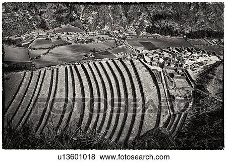 Stock Photo - Pisac ruins: detail monochrome view of agricultural terracing and Inca citadel, with modern town beyond, Sacred Valley, Cuzco, Peru. Fotosearch