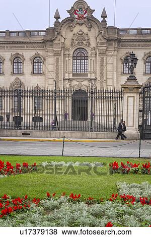 Plaza del Armas: detail of Palacio de Gobierno, ornate stone facade and wrought iron gates, typical of Spanish Colonial era, with uniformed presidentail guards, two tourists, landscaped gardens with red flowers, Lima, Peru View Large Photo Image Stock Photo - Plaza del Armas: detail of Palacio de Gobierno, ornate stone facade and wrought iron gates, typical of Spanish Colonial era, with uniformed presidentail guards, two tourists, landscaped gardens with red flowers, Lima, Peru. Fotosearch