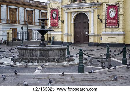 Stock Photography - Plaza of San Francisco monastery: detail of entranceway with stone fountain, and Spanish colonial buildings beyond, Lima, Peru. Fotosearch